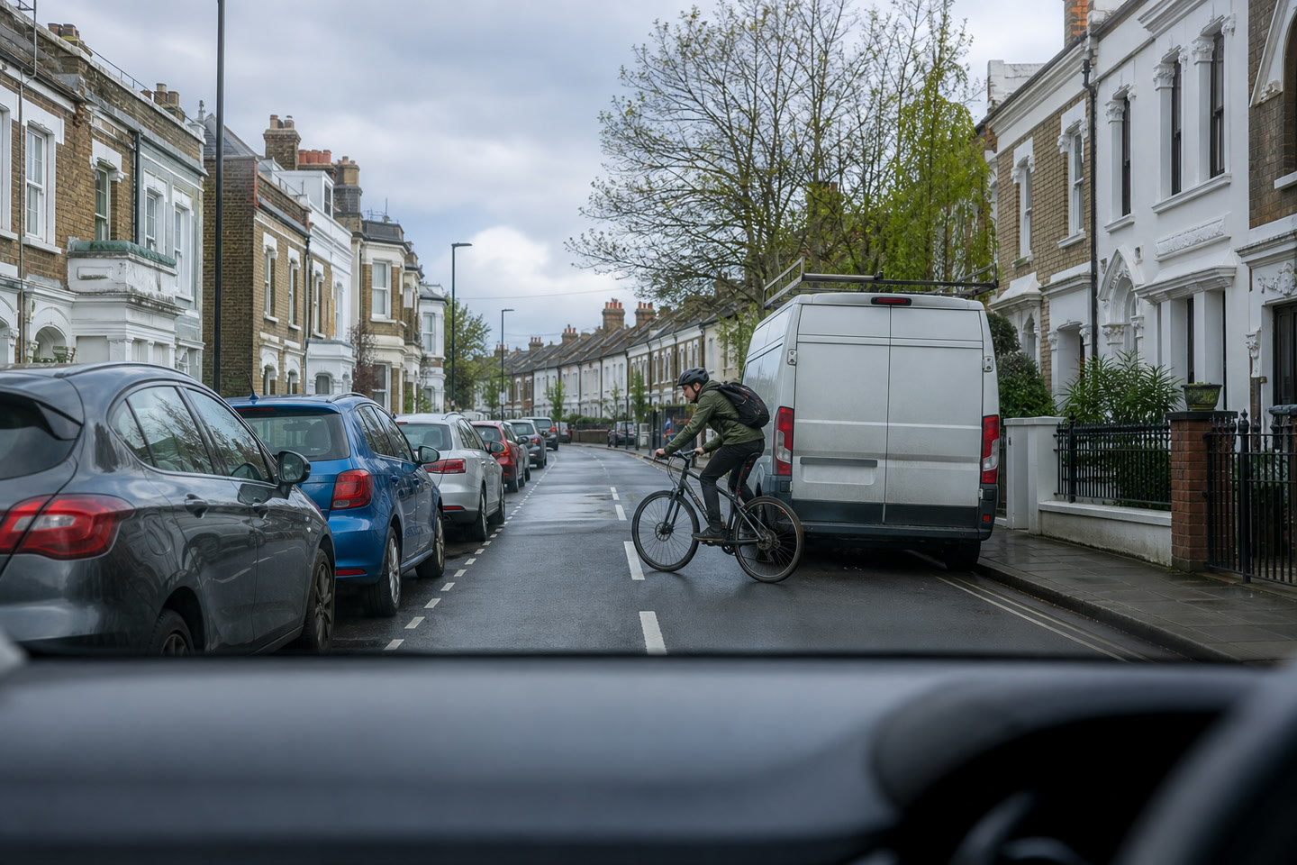 A cyclist emerging beside a parked van on a residential road